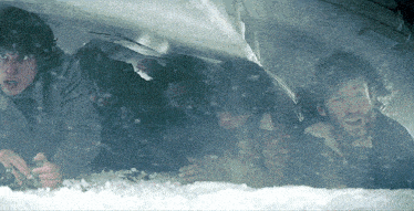 a group of people are huddled under a tarp while it snows