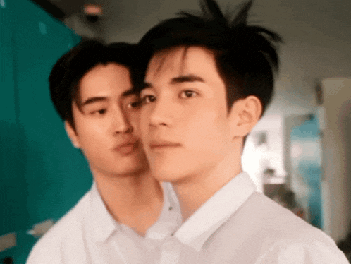 two young men in white shirts are standing next to each other and looking at the camera .