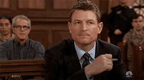 a man in a suit and tie is sitting in a courtroom with nbc written on the bottom