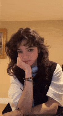 a woman with a bracelet on her wrist is sitting with her hand on her face .
