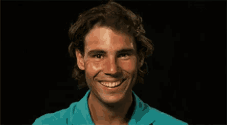 a close up of a man 's face with a blue shirt on smiling .