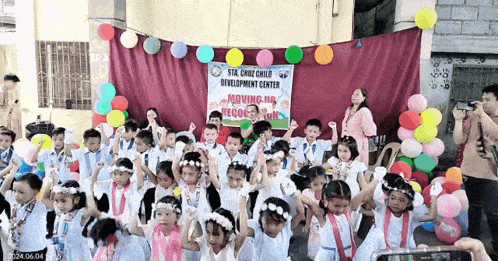 a group of children are dancing in front of a sign that says moving on