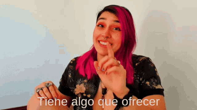 a woman with pink hair holds her finger to her mouth with the words tiene algo que ofrecer behind her