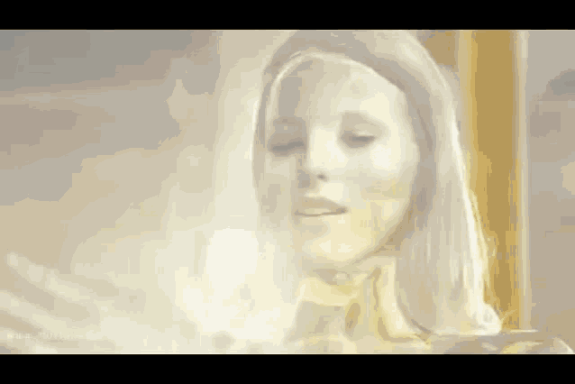 a woman with white hair is standing in front of a window and looking at something .