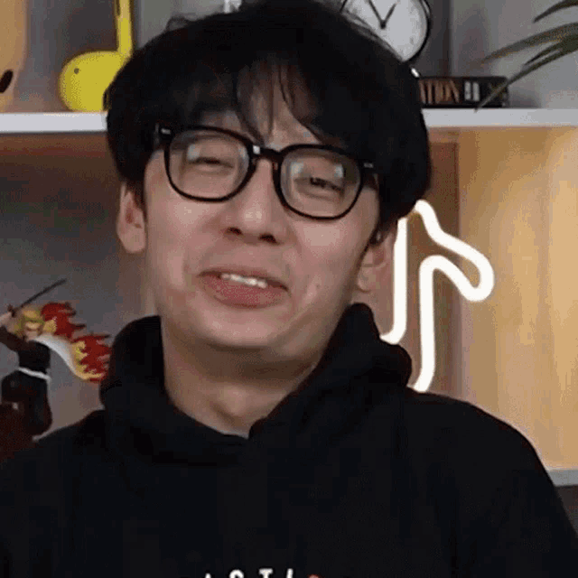 a man wearing glasses and a black hoodie making a funny face