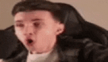 a man is sitting in a chair with his mouth open and a surprised look on his face .
