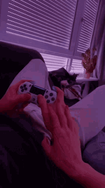a person laying on a couch playing a video game controller