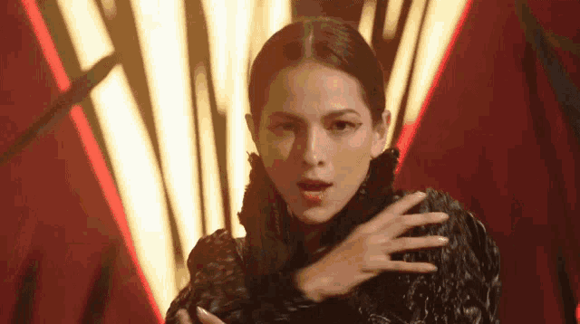 a woman in a black fur coat is dancing in front of a red and yellow background