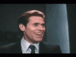 a man in a suit and tie is smiling in a dark room .