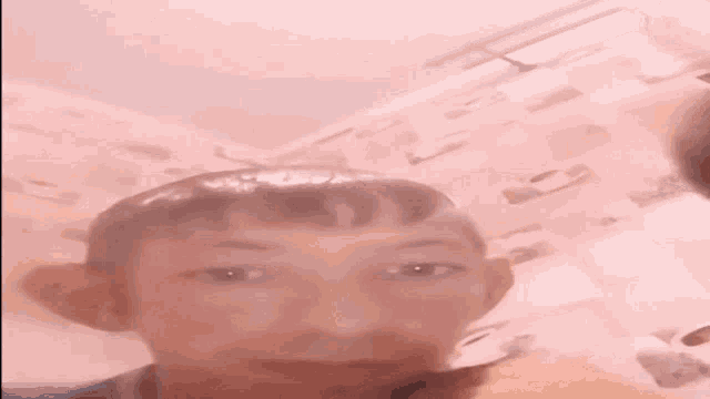 a young boy is taking a selfie in front of a pink background .