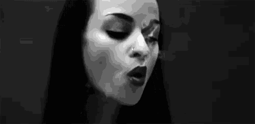a black and white photo of a woman smoking a vape .