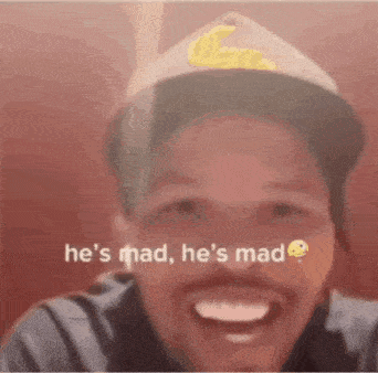 a man wearing a hat is laughing with the words `` he 's mad , he 's mad '' written on his face