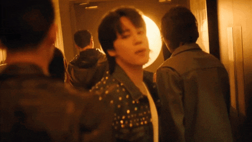 a man in a studded jacket is standing in a dark hallway