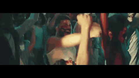 a group of people are dancing in a club with their arms in the air .