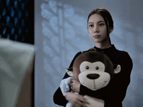 a woman holds a stuffed monkey in her hands