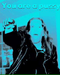 a woman in a black jacket is pointing at the camera with the words " you are a pussy " below her