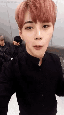 a young man with pink hair is taking a selfie with his phone