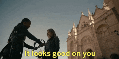 a man is holding a sword in front of a woman and says it looks good on you