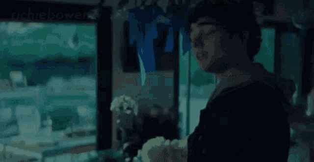 a man is standing in front of a window in a dark room holding a yellow object .