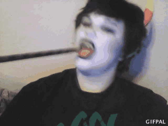 a person with white paint on their face is wearing a green shirt that says gifpal