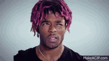 a young man with pink dreadlocks is making a funny face .