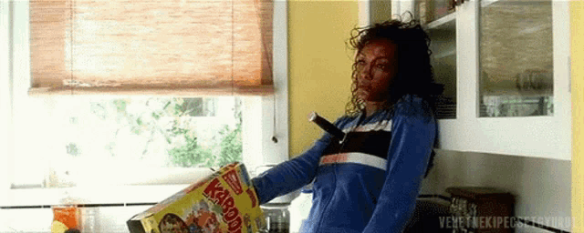 a woman is holding a box of kahlua cereal in her hand .