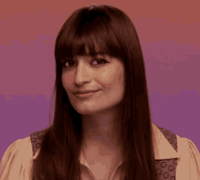 a woman with long brown hair and bangs is smiling .