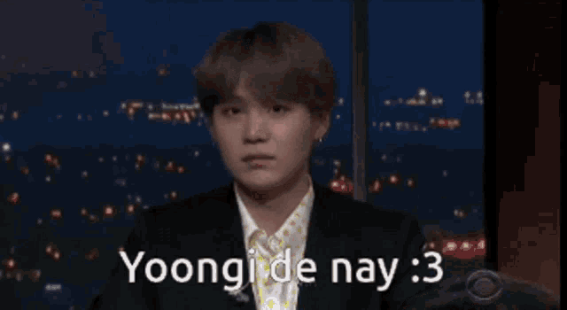 a man in a suit is waving his hands and says yoongi de nay