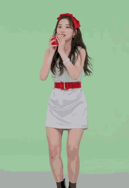 a woman in a dress is holding a red apple in her hand