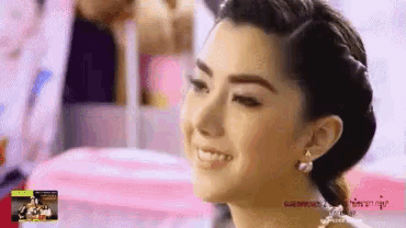 a woman wearing a braided hairstyle and earrings is smiling