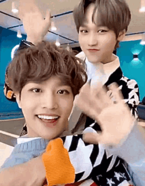 two young men are making a heart shape with their hands and smiling for the camera .