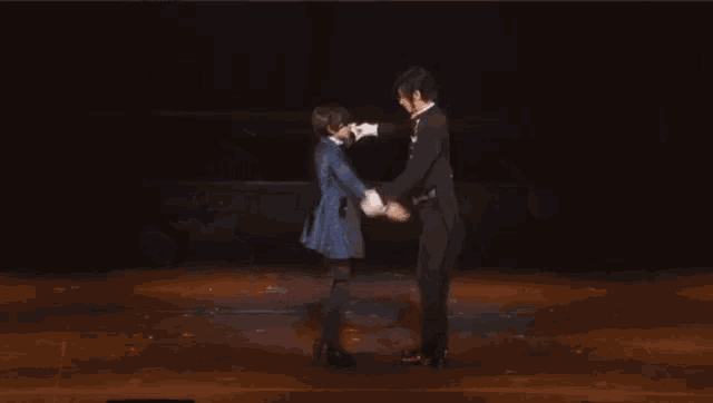 two men in tuxedos are dancing together on a stage