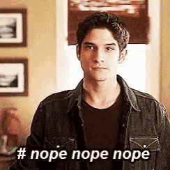 a man in a denim jacket is standing in front of a window and says nope nope nope .