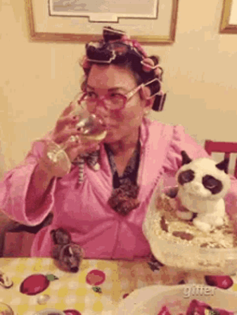 a woman with curlers in her hair is drinking a glass of wine while sitting at a table .