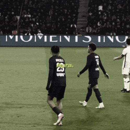 two soccer players on a field with a banner that says moments inu
