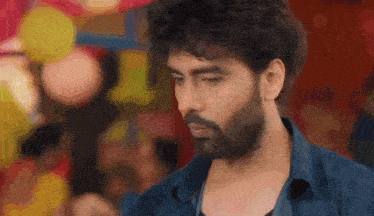 a man with a beard and curly hair is looking at the camera .