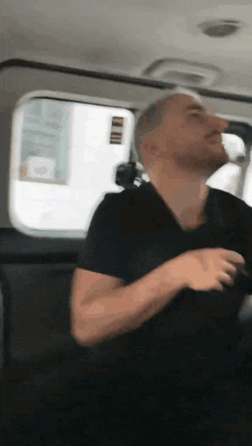 a man in a black shirt is sitting in the back of a car