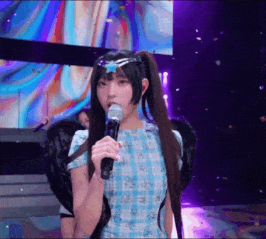 a girl with pigtails is holding a microphone on stage