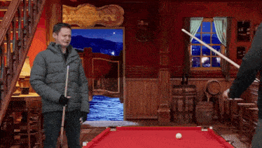two men are playing pool in a saloon with a sign that says saloon