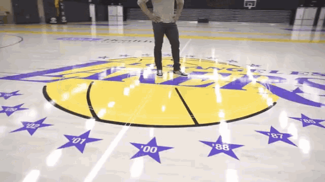 a man stands on a basketball court with purple stars and the number 88 on the floor