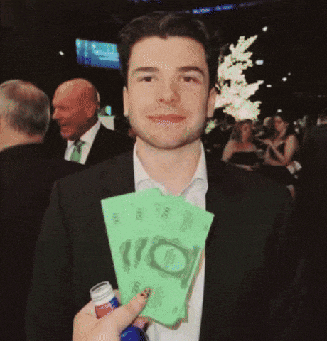 a man in a suit is holding a bunch of money and a bottle