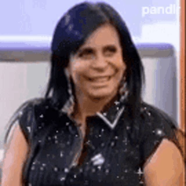 a woman with long black hair is smiling while wearing a black shirt .