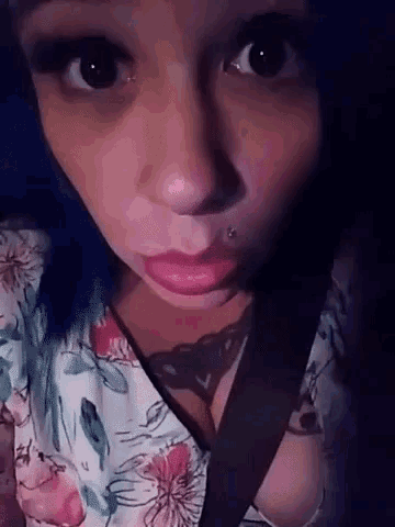 a woman with blue hair is wearing a floral shirt and a seat belt around her neck .