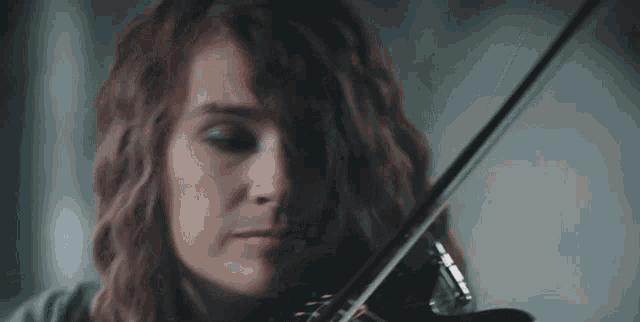 a woman is playing a violin in front of a window .