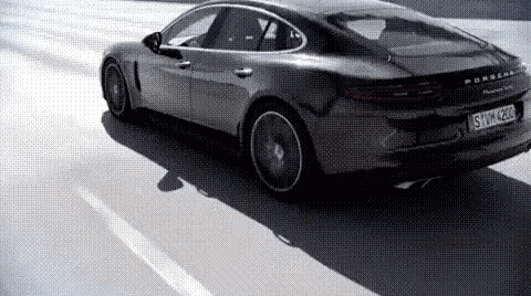 a gray porsche panamera is driving down a road .