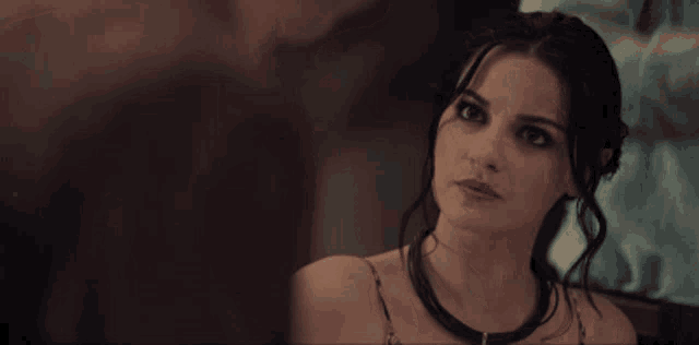 a woman in a black dress is looking at a man in a dark room .