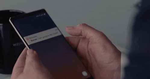 a person is holding a cell phone with a message from roman on the screen