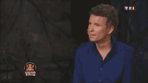 a man in a blue shirt is making a funny face in front of a tv screen .