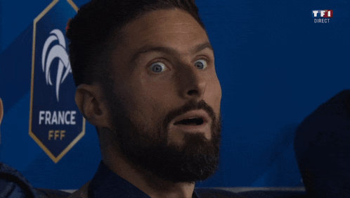 a man with a beard looks surprised in front of a france logo