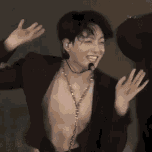a shirtless man is dancing on a stage with his arms outstretched .